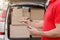 Courier are notes to tablet delivered parcel, close up, car with boxes near