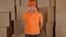 Courier in orange uniform delivering damaged parcel to customer. Brown cartons background. Flaw and unprofessional work