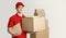 Courier and package in warehouse. Deliveryman holding box and tablet near stack of parcels