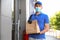 Courier in protective mask and gloves with order near front door. Restaurant delivery service during coronavirus quarantine