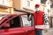 Courier in protective mask and gloves with pizza boxes near car. Food delivery service during quarantine