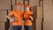 Couriers in orange uniform standing against brown cartboard boxes backround. Delivery company personel, 4K clip