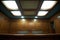 a courtroom witness box empty under ceiling lights