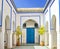 Courtyard at El Bahia Palace, Marrakech, Morocco. there are white walls and columns with blue signs and blue doors