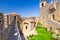 Courtyard with green grass lawn of Prima Torre Guaita first medieval tower with stone brick fortress wall with merlons, San Marino