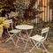 Courtyard metal chairs and table in a serene, peaceful, lush, private backyard at home in autumn. Patio furniture set in