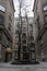 Courtyard with old buildings facades and bare tree in the middle. Exterior of ancient houses. Urban landmark and cityscape.