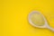 Couscous groats made of durum hard wheat in wooden spoon isolated on yellow background, top view