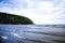 Cove with sunbathers and tourists on the beach on beautiful picturesque day with mountains