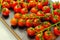 Covered with drops of water, fresh tomatoes with sprigs on wood