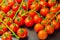 Covered with drops of water, fresh tomatoes with sprigs on wood