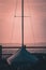 A covered sailing boat and mast at sunset