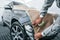 Covering car by brown cloth. Caucasian automobile repairman in uniform works in garage