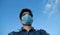 Covering face with mask to protect from covid19 disease. Photo about man wearing mask isolated on a blue sky. Selfie with mask.