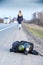 COVID-19. A black gas mask and a backpack lie on the side of an asphalt highway