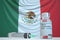 COVID-19 coronavirus disease vaccine vial and syringe against the Mexican flag. Medical research and vaccination in