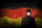 COVID-19 coronavirus epidemic in germany. Silhouette of man in medical mask on abstract german flag background. Global COVID-19