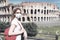 COVID-19 coronavirus in Italy, woman in face medical mask next to empty Colosseum in Rome. Tourist landmarks closed due to corona