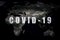 COVID-19 coronavirus pandemic, name COVID-19 on dark global map. SARS-CoV-2 coronavirus outbreak in world. Rapid spread of deadly