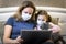 COVID-19 coronavirus quarantine concept, woman in face mask working with laptop staying home. Family using computer during