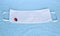 Covid-19 disposable 3-layer white filter mask with lucky charm  ladybird, blue towel as a background