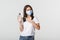 Covid-19, health and social distancing concept. Smiling cute brunette woman in medical mask advice using hand sanitizer