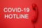 Covid-19 Hotline. Handset and text on red background, top view