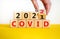 Covid-19 pandemic in 2022 symbol. Doctor turns a wooden cube and changes words `covid 2021` to `covid 2022`. Beautiful yellow