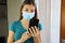 COVID-19 Pandemic Coronavirus Woman Home Isolate Quarantine Wearing Surgical Mask with Mobile Phone Reading Information about