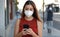 COVID-19 Pandemic Coronavirus Young Woman Wearing KN95 FFP2 Mask Using Smart Phone App in City Street to Aid Contact Tracing