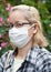 COVID-19 - Portrait of middle aged mixed race blonde woman with eyeglasses wearing white surgical mask