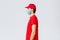 Covid-19, self-quarantine, online shopping and shipping concept. Profile of serious young courier in red uniform of