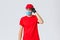 Covid-19, self-quarantine, online shopping and shipping concept. Sassy delivery man in red uniform and mask with gloves