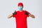 Covid-19, self-quarantine, shopping and shipping concept. Enthusiastic and happy courier in red uniform, gloves and face