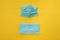 COVID-19 two disposable surgical face masks on yellow background