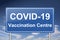 Covid-19 vaccination centre traffic sign, blue billboard under cloudy sky illustration