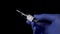 COVID-19 vaccine in the hand of a researcher in blue medical gloves close-up on a black background.