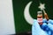 COVID-19 vaccine. Hands in blue medical gloves holding a vaccine bottle and syringe with Pakistan flag