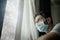 Covid-19 virus lockdown - sad and worried man in medical mask thinking and feeling scared in quarantine following stay at home