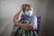 Covid-19 virus spreading disease - scared and sad mature woman with grey hair in hospital patient gown and mask infected by