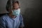Covid-19 virus spreading disease - scared and sad mature woman with grey hair in hospital patient gown and mask infected by