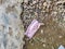 COVID-19 Waste or Litter Concept. Discarded Pink Medical Face Mask Thrown Away After Use on the street footpath