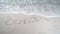 Covid 19 written in Sand being erased by waves. White sand beach