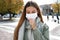 COVID-19 Young woman coughs with surgical mask during coronavirus pandemic disease in city street. Girl having symptoms like