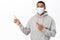 Covid awareness, healthcare concept. Portrait of african american guy in medical mask, pointing finger left, showing