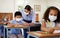 Covid, education and learning with a teacher wearing a mask and helping a male student in class during school. Young boy