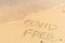 Covid free written on the shore, on the sand of a beach