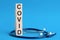 Covid word written on wooden blocks and stethoscope on light blue background