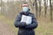 Covidiot concept. Blurred young man in protective mask holds many rolls of toilet paper outdoors in spring wood