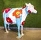 Cow decorated with yellow red orange magenta flower and cyan strips and cyan strips in a store